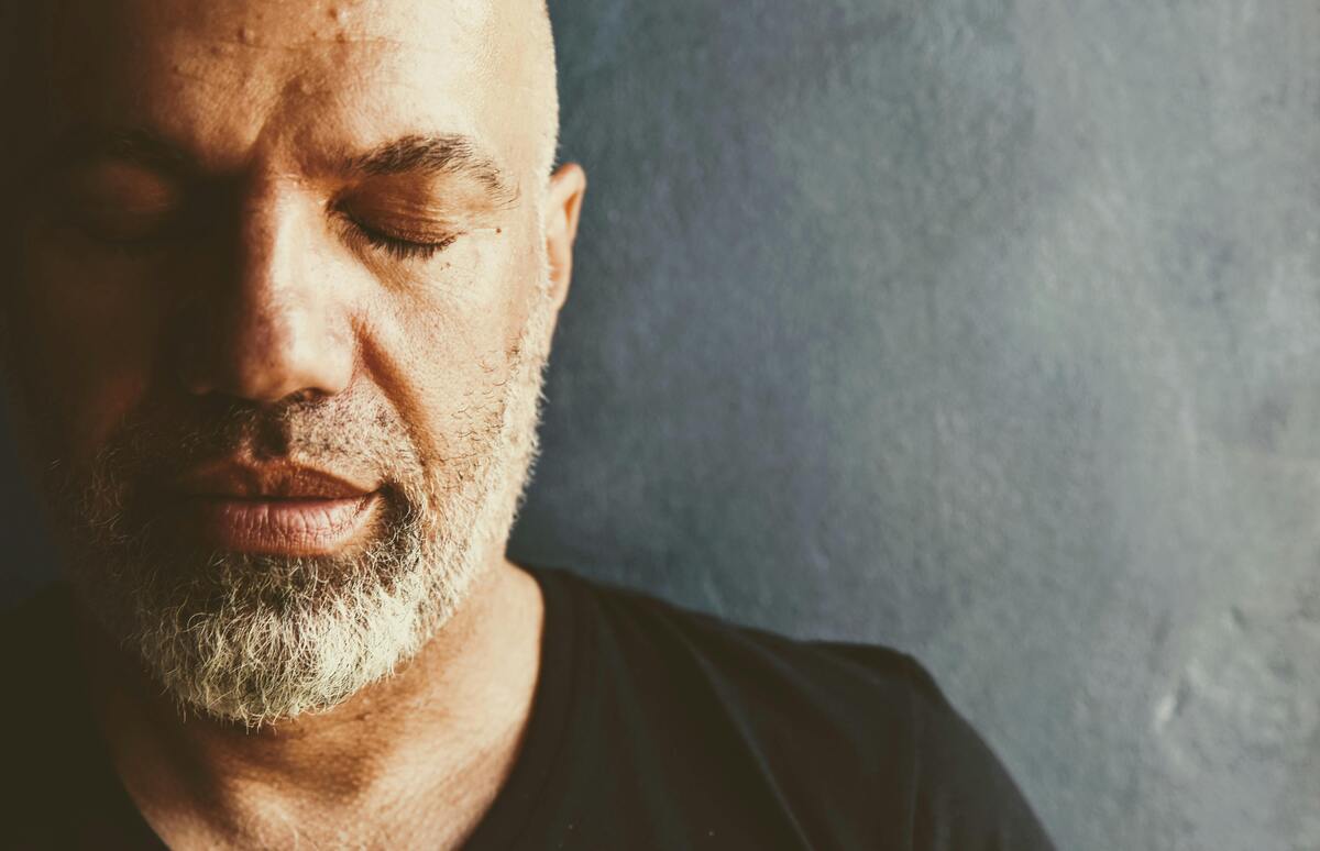 man standing with eyes closed as though in deep thought