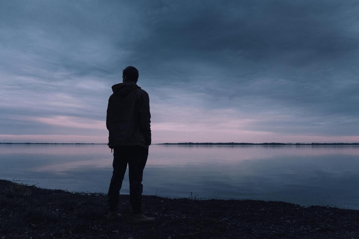 man looking out over water at sunset